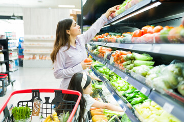 Focused mother grocery shopping with her little girl