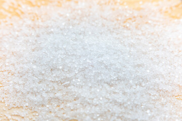 Background with salt scattered on a wooden surface. Close-up of blurry salt granules in soft focus...