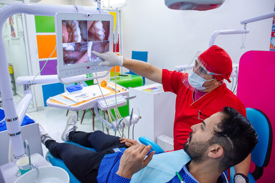 Dentist showing to his patient dental images on a screen in modern dental office