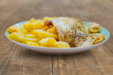 Fried fish in oil with herbs and spices with homemade fried potato. Simple, homemade food on wooden background.