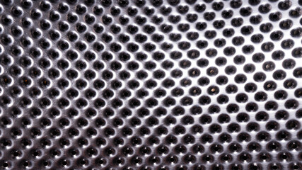 Shiny metal surface with lots of round holes. Perforated stainless metal. Fragment of a washing machine drum