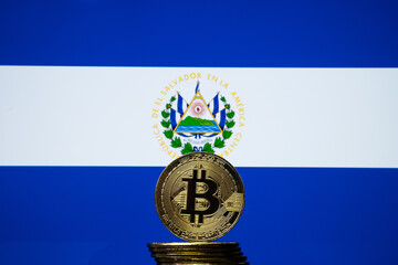 Bitcoin representation coin placed in front of blurred Salvador's national flag. El Salvador is the first country to adopt bitcoin as legal tender. Concept. - obrazy, fototapety, plakaty