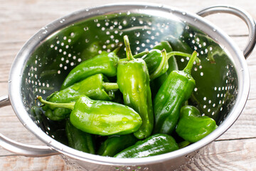 Padron pepper in a colander on a table. A pile of raw Padron peppers typical of Spain