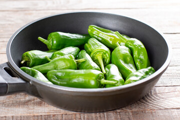 Fresh green pimientos or peppers de padron in frying pan. Fried in olive oil, and sprinkled with sea salt is a typical tapa meal in Spain. selected focus