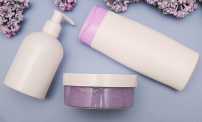 Three cosmetic bottles with violet lilac on background