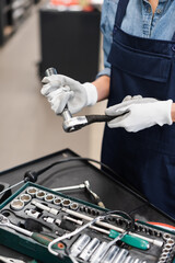 close up view of mechanic hands in gloves holding wrench in garage