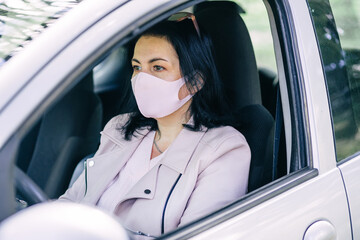 Young woman driving a car with a protective mask on her face. Health care, protection against viruses, flu, coronavirus.