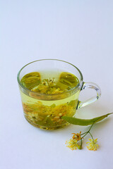 hot Tea from Linden flowers in glass cup with bloom flowers isolated on white background. healthy herbal drink in mug on the table. warming liquid.