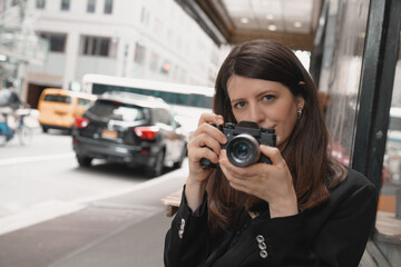 Young woman holding photo camera in hands outside. Closeup face shot