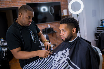 barber observing young man's hair. in barber shop for all ages and styles. shaping the haircut.