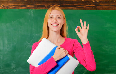 Back to school. Education. Smiling female teacher in classroom shows Sign ok. University. College.