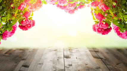 Wooden table and blooming roses blurred summer background. Summer concept background
