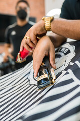 barber holding hair clippers.red and black hair clippers in barber's chair years. chairs covered by barber's blanket.