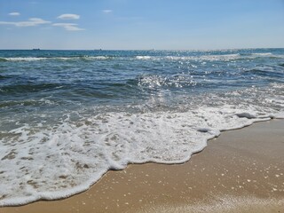 morning sea, foamy Wave rolls over the Sandy coast, ebb and flow, relaxation, blue sky with clouds,...