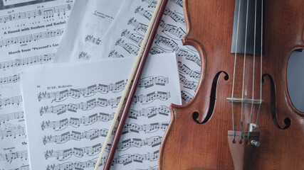 Fototapeta na wymiar Close up detail on violin body, bow and music notes background. Classic instrument with copy space area 