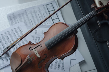 Close up detail on violin body, bow and music notes background. Classic instrument with copy space area 