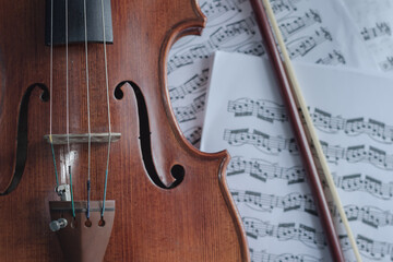 Close up detail on violin body, bow and music notes background. Classic instrument with copy space...