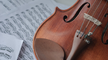Naklejka premium Close up detail on violin body, bow and music notes background. Classic instrument with copy space area 
