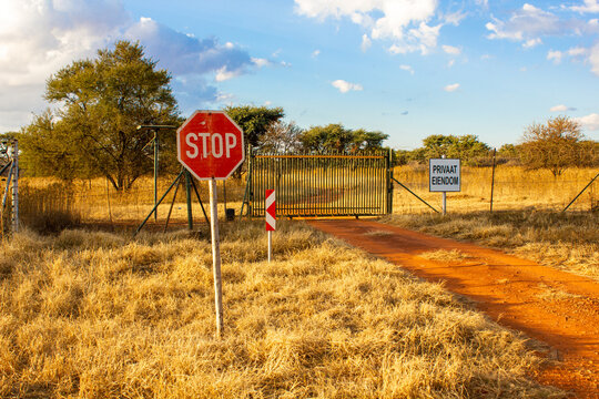 A green gate with a stop sign and a private property sign. Private property is written in Afrikaans "Privaat Eiendom"