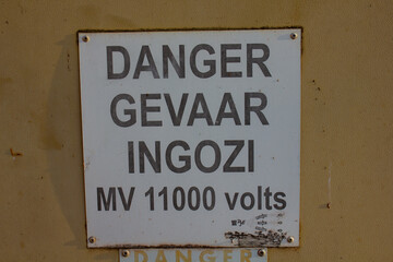 An 11000 volt Electrical sign  with the word danger written in three languages.  English, Afrikaans, Zulu. 