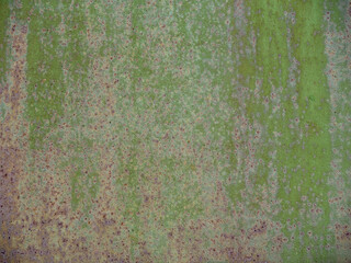 The texture of a rusty metal sheet of iron with a peeling pale green paint. Garage metal door, gate background close-up.