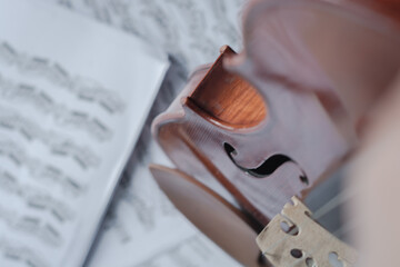 Close up detail on violin body, bow and music notes background. Classic instrument with copy space...