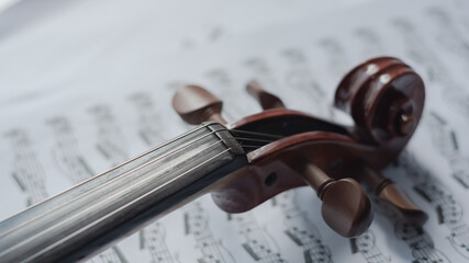 Naklejka premium Close up detail on violin body, bow and music notes background. Classic instrument with copy space area 