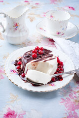 Traditional blancmange almond pudding with currant berries, chocolate cream and crumples served as close-up in a classic design plate