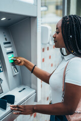 African american woman using credit card and withdrawing cash at the ATM