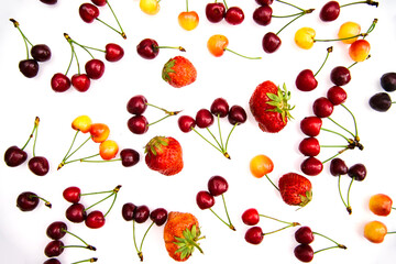 Red and yellow ripe cherries and strawberries. Berries are randomly scattered on a white background.