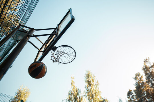 Basketball court on nature. Ball throwed into basketball hoop on summer sky background. Aiming, goal concept