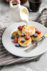 Sour cream is poured onto cheesecakes with berries