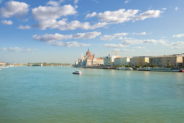 Naklejka premium Afternoon on the River Danube with the Danube promenade and the Parliament Building on the banks of Danube and a small boat in the river