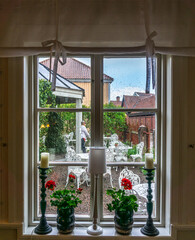 Window decorated with blooming flower and candlestick with a view toward backyard