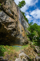 Obraz premium View of the mountain waterfall from the side of the mountain gorge against the backdrop of bright colors of nature