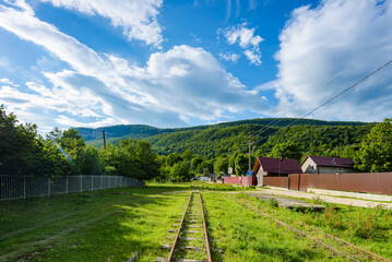 An old narrow-gauge railway among the colorful vegetation of a mountain village