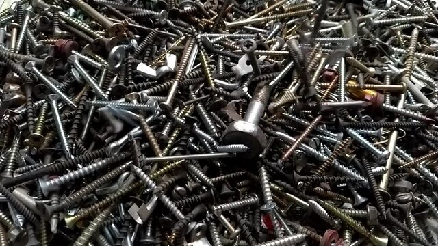 Recycle metal waste building material. Bolts, screws, nails in slow motion
