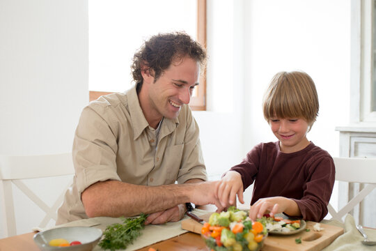 Family preparing a healthy meal in the kitchen at mediterranean home.
