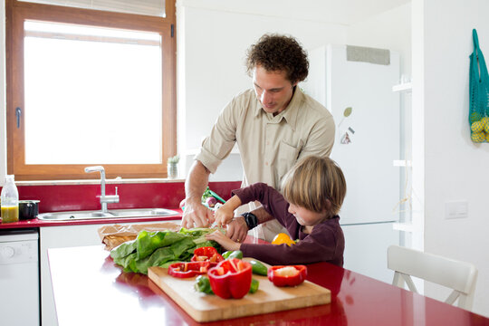 Family preparing a healthy meal in the kitchen at mediterranean home.
