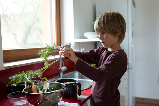 Boy washing the vegetables in the kitchen
