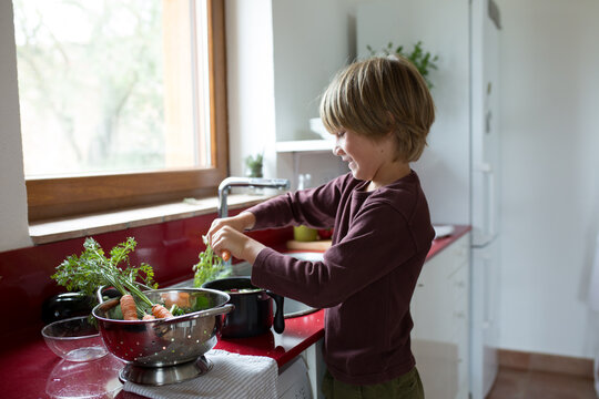 Boy washing the vegetables in the kitchen
