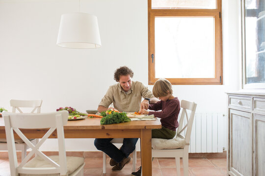 Family preparing a healthy meal in the kitchen at mediterranean home.
