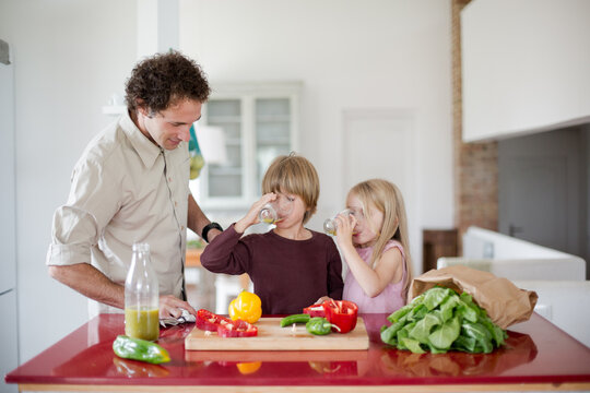 Family preparing a healthy meal in the kitchen at mediterranean home.
