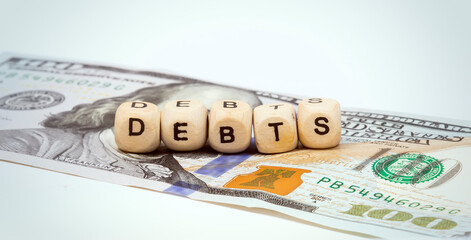 Wooden cubes with letters on a hundred dollar bill. Debts