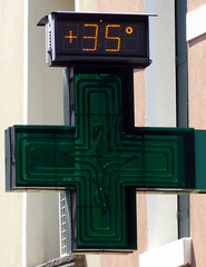 Digital street thermometer on a pharmacy sign displaying 35 degrees celsius. Very hot day concept