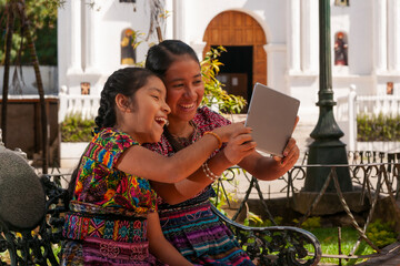 Happy indigenous girls taking selfie with tablet in a park