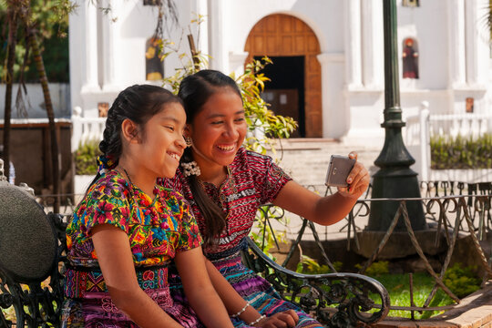 Happy indigenous girls taking selfies with a smartphone in a park.