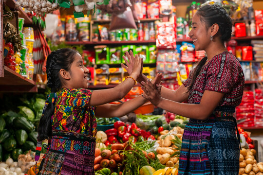 Two indigenous girls playing clapping games in a grocery store.