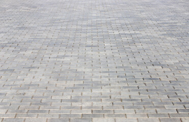 Sidewalk paved with gray rectangular tiles in perspective