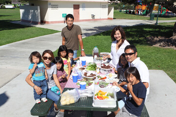 Two families enjoying BBQ in the park